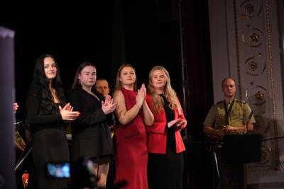 Artyści i orkiestra wojskowa na scenie.