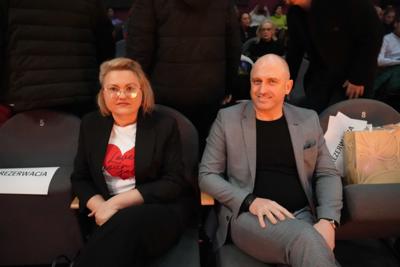 Dwie uśmiechnięte osoby siedzą na widowni.