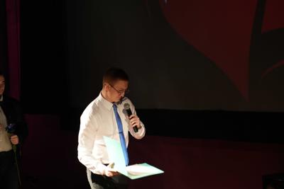 Chłopak w krawacie i okularach z mikrofonem.
