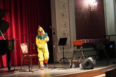 Chłopiec w stroju kurczaka na scenie. Wokół instrumenty muzyczne.