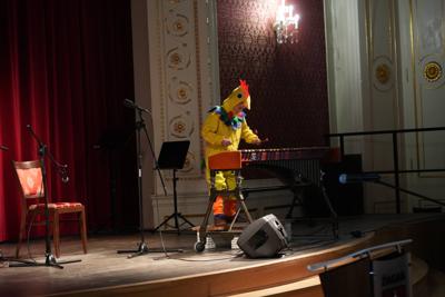 Chłopiec w stroju kurczaka gra na ksylofonie na scenie.