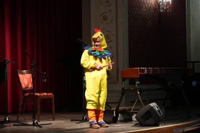 Chłopiec w stroju kurczaka na scenie. Wokół instrumenty muzyczne.