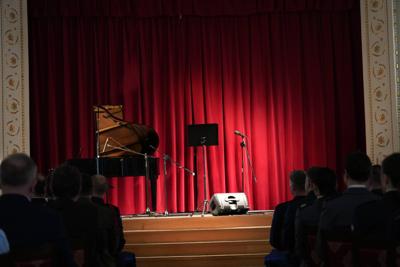 Publiczność spogląda na scenę, na której stoją instrumenty muzyczne.