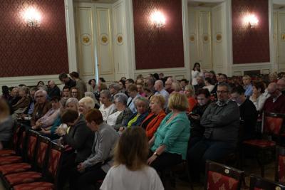 Publiczność siedzi na krzesłach.