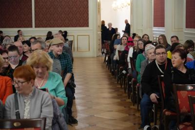 Publiczność siedzi na krzesłach.