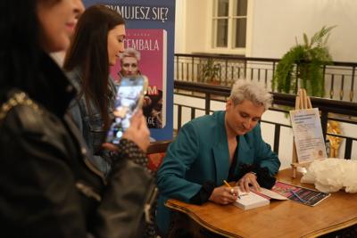 Autor na spotkaniu autorskim podpisuje dla pani jej egzemplarz książki.
