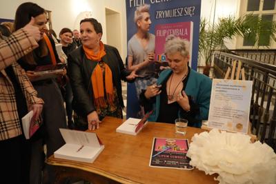 Spotkanie autorskie, autor siedzi przy stole.