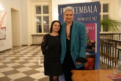 Spotkanie autorskie, autor pozuje do zdjęcia z panią. Uśmiechają się.