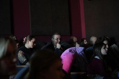 Publiczność siedząca w ciemnym pomieszczeniu ogląda występy.