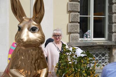 Pani stojąca przy dużej, złotej figurze króliczka wielkanocnego.