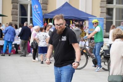 Pan pozujący do zdjęcia. W tle grupa ludzi.