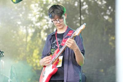 Chłopak gra na gitarze na scenie.