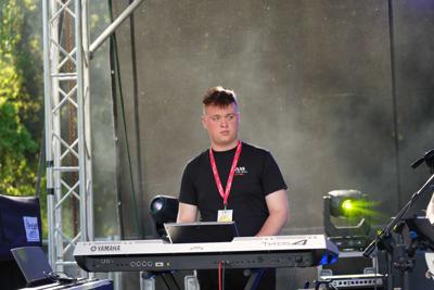 Chłopak gra na keyboardzie na scenie.