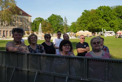 Grupa osób przy barierkach pod sceną.