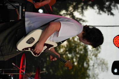 Chłopak grający na gitarze na scenie.