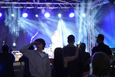 Grupa ludzi pod sceną, osoba pozuje do zdjęcia.