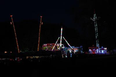 Atrakcje rozrywkowe rozświetlają park wieczorem.