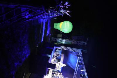 Grupa osób przy barierkach pod sceną. Oglądają występ grupy muzycznej.