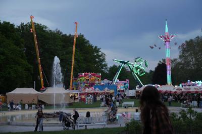 Atrakcje rozrywkowe rozświetlają park wieczorem.