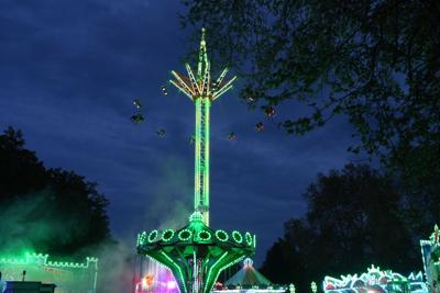 Atrakcje rozrywkowe rozświetlają park wieczorem.