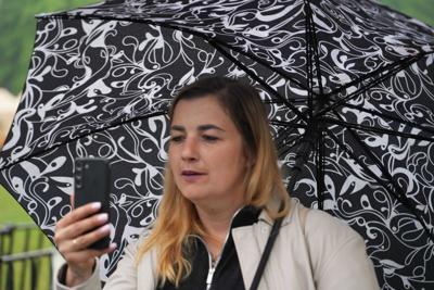 Pani z parasolką robi zdjęcie telefonem.