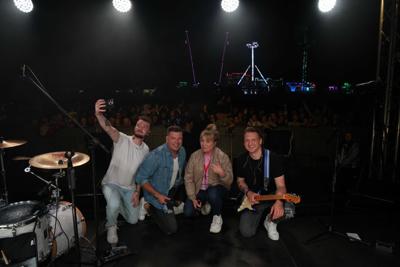 Grupa muzyczna pozuje do zdjęcia z publicznością.