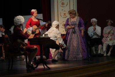 Artyści w historycznych przebraniach występują na scenie. Za nimi orkiestra.