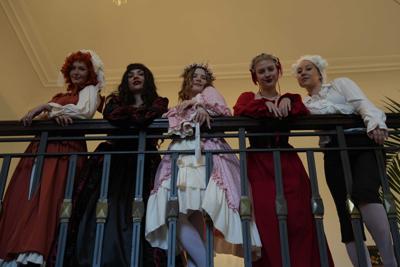 Osoby w historycznych przebraniach stoją przy barierce.