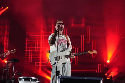 Mężczyzna z gitarą śpiewa na scenie.