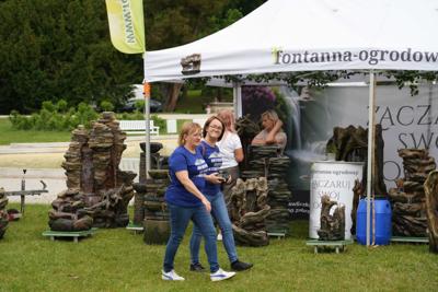 Dwie panie idą przed stoiskiem z fontannami ogrodowymi.