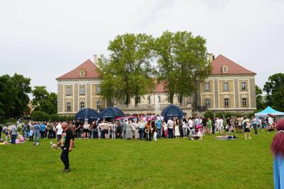 Ludzie zgromadzeni przed namiotami znajdujący się pod budynkiem pałacu.