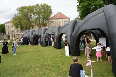 Grupa osób zebrana pod namiotami.