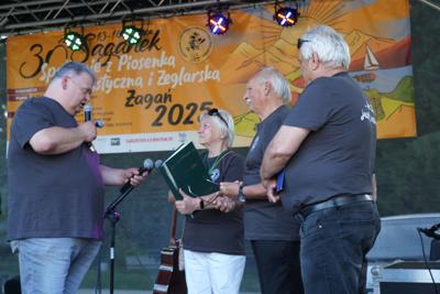 Grupa osób zwróconych do siebie na scenie.