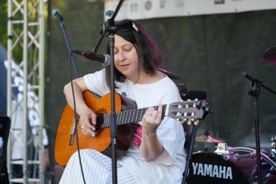 Pani występuje z gitarą na scenie.