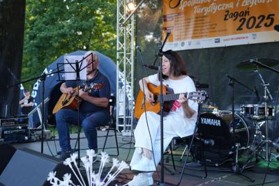 Dwie osoby występują z gitarami na scenie.