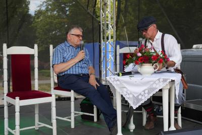 Panowie na scenie przemawiają do mikrofonów.