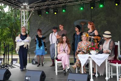 Staromodnie ubrane osoby znajdują się na scenie.