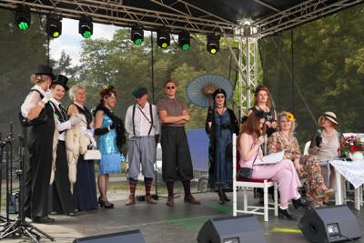 Staromodnie ubrane osoby znajdują się na scenie.