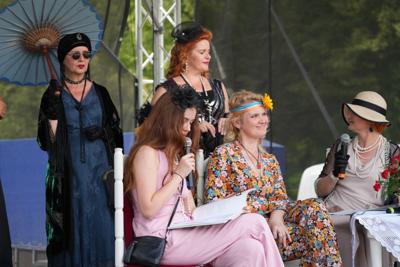 Staromodnie ubrane osoby znajdują się na scenie.