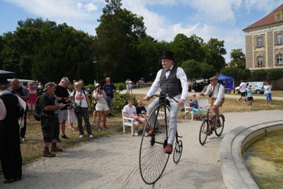 Pan jedzie na bicyklu, za nim pan na rowerze z trąbką.