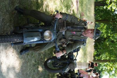 Pan w mundurze siedzi na starym motorze.
