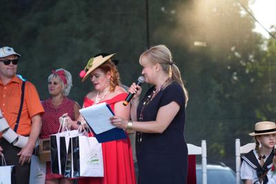 Staromodnie ubrane osoby na scenie - obok pani z mikrofonem.