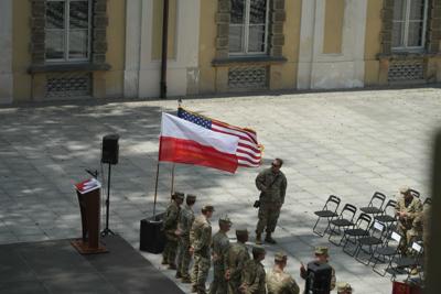 Żołnierze stojący przy flagach Polski i Stanów Zjednoczonych, przed nimi ustawione krzesła.