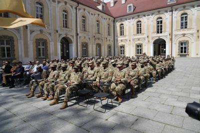 Grupa żołnierzy usadowiona na krzesłach ustawionych na dziedzińcu pałacu.