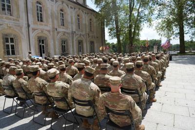 Grupa żołnierzy usadowiona na krzesłach ustawionych na dziedzińcu pałacu.