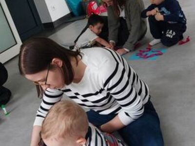Dzieci z opiekunami wykonują pracę plastyczną.