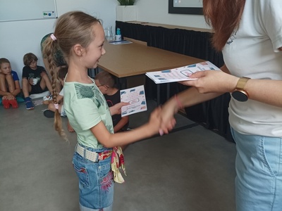 Dziecko odbiera certyfikat udziału w półkoloniach.