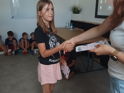 Dziecko odbiera certyfikat udziału w półkoloniach.