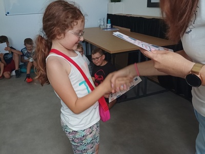 Dziecko odbiera certyfikat udziału w półkoloniach.