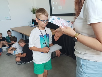 Dziecko odbiera certyfikat udziału w półkoloniach.